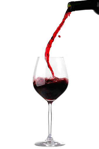 Red wine pouring from bottle into glass isolated on white background