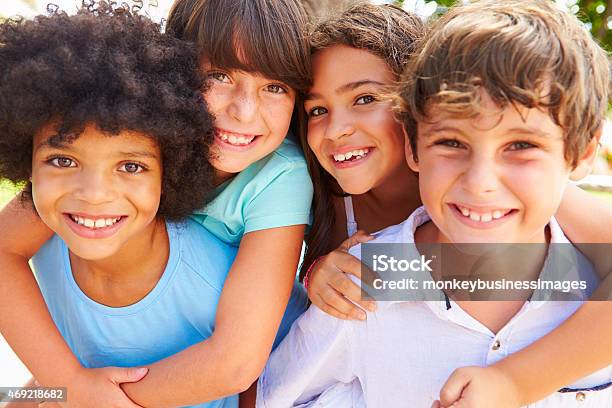 Group Of Children Giving Each Other Piggyback Rides Stock Photo - Download Image Now