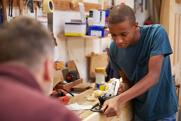 istock Carpenter With Apprentice Planing Wood In Workshop 469219750