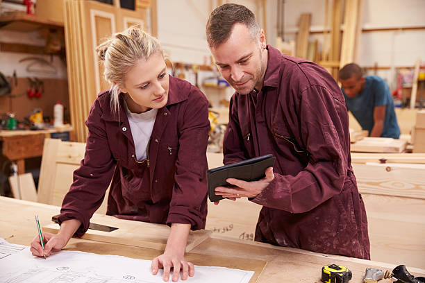 istock Carpenters wearing overalls looking at design plans 469220092