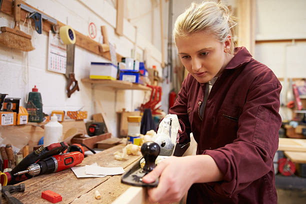 istock Female Apprentice Planing Wood In Carpentry Workshop 469223326