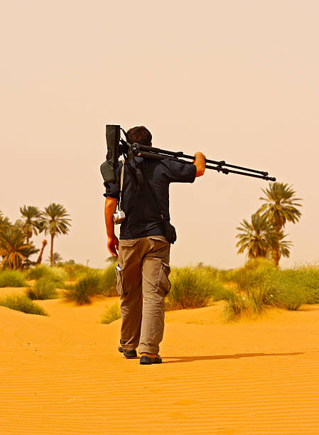 istock Birdwatcher with telescope walking in Sahara Desert 469223402