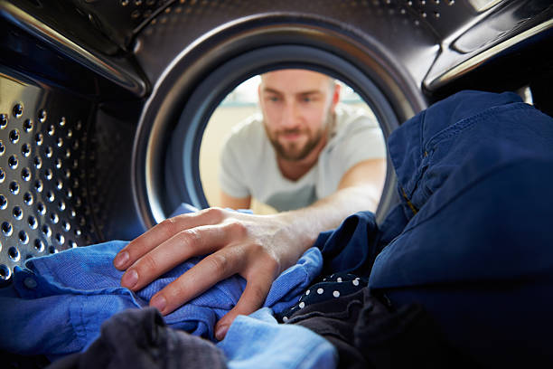 uomo facendo lavanderia raggiungere in lavatrice - mechanical man foto e immagini stock