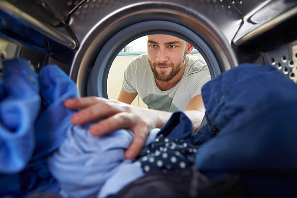 homem fazendo chegar dentro de máquina de lavar roupa - clothing smiling household equipment viewpoint - fotografias e filmes do acervo