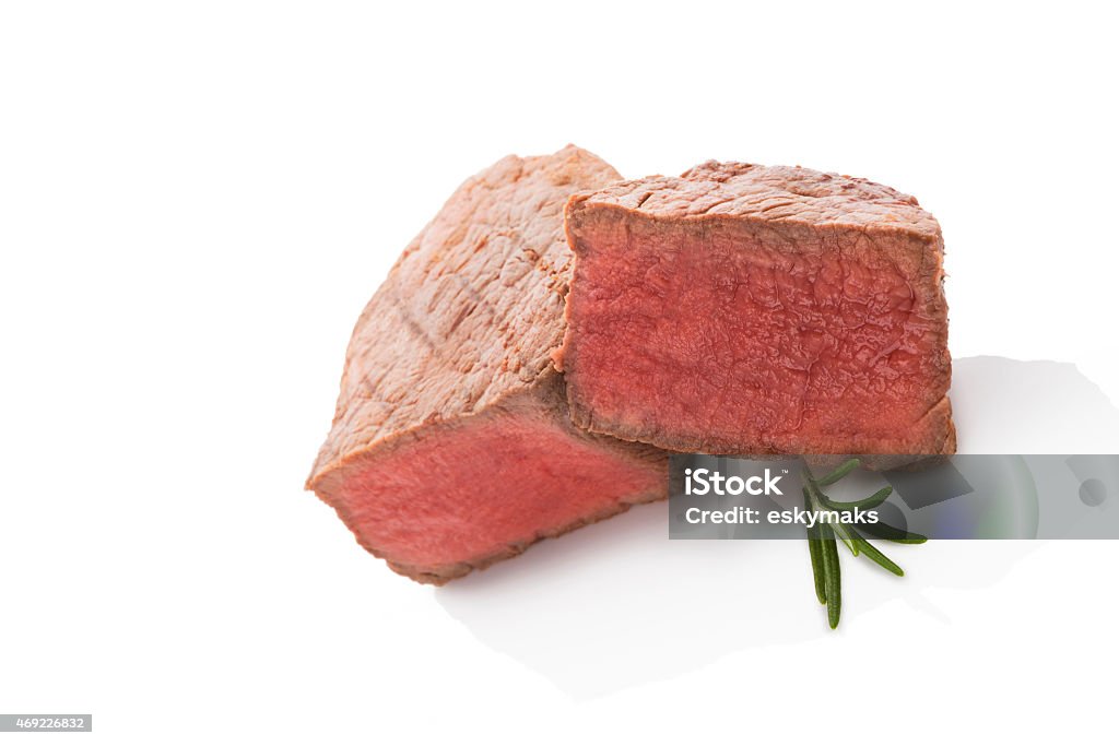 Big steak isolated on white. Big tenderloin steak with fresh herbs isolated on white background. Culinary steak eating. 2015 Stock Photo