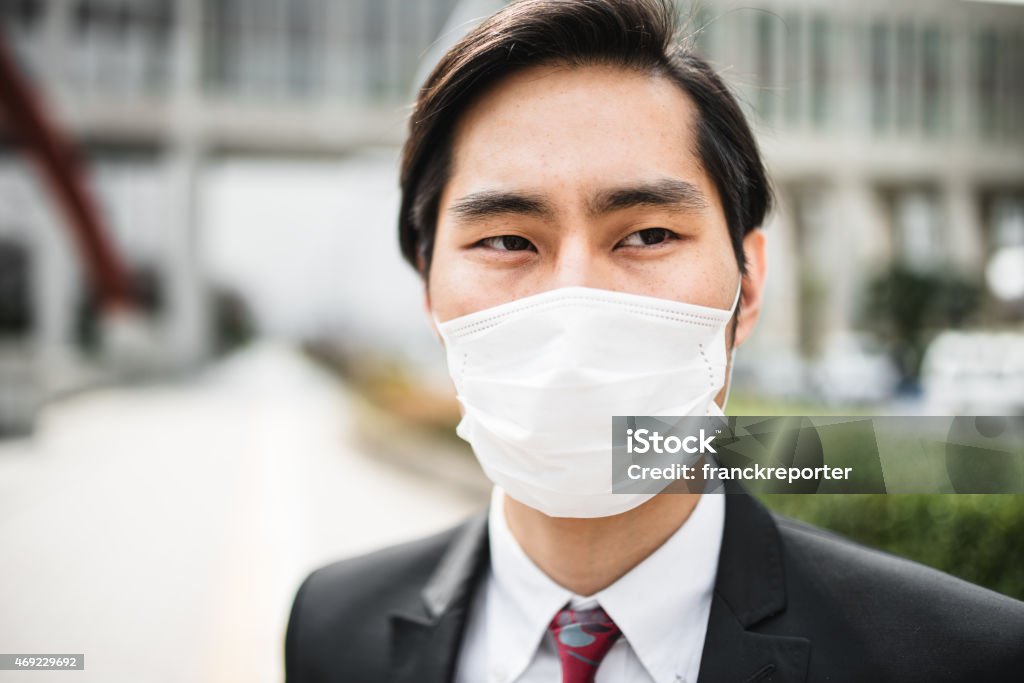 japanese businessman standing on the city with a pollution mask japanese businessman standing on the city Cold And Flu Stock Photo