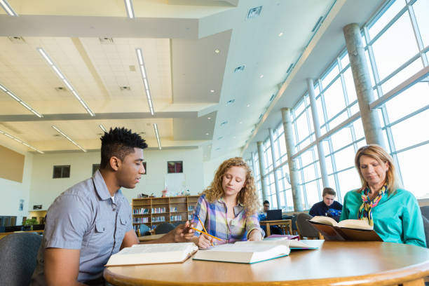 istock High school student being tutored in library while mom waits 469231214