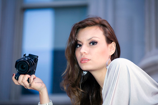 Latin woman in her early twenties holding camera.