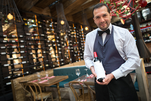 Sommelier holding a bottle of red wine at a cellar
