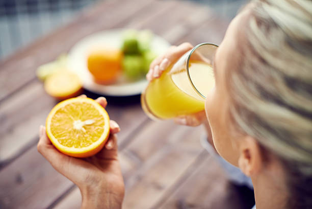 начать день с апельсиновый сок - women juice drinking breakfast стоковые фото и изображения