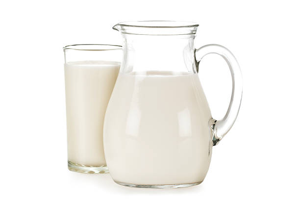 Glass and pitcher filled with milk. stock photo