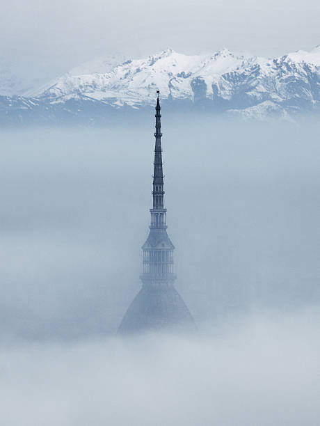 Mole Antonelliana surrounded by fog, snow capped Alps on background stock photo