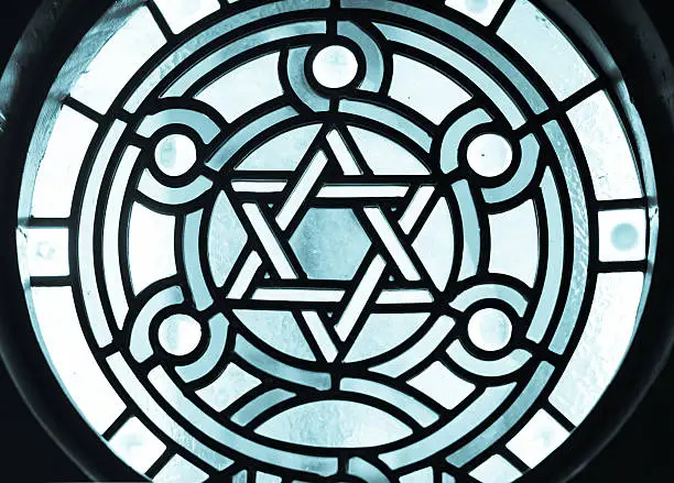 Stain-glass Window in 19 century Synagogue. Stain-glass with a dramatic back light overtone. The Star of David, known in Hebrew as the Shield of David or Magen David, is the quintessential symbol of Jewish identity.