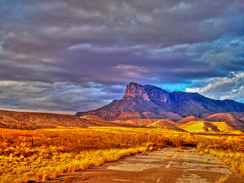 The highest point in Texas, called Guadalupe Peak, Signal Peak, or El Capitán, taken between Carlsbad, NM and El Paso TX with dark storm clouds in the background and old highway in the foreground