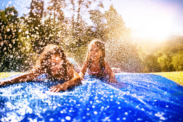 Littel girls sliding down a water slide happily stock photo