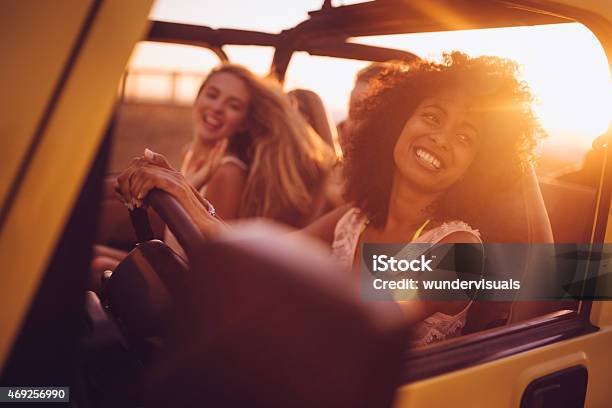 Afro Girl With Friends On A Road Trip At Sunset Stock Photo - Download Image Now - Car, Driving, Road Trip