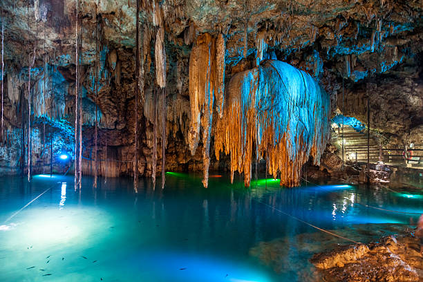 A view of caverns and rocks in Mexico lovely cenote with transparent turquoise waters and large stalactites. ISO 1600 with slight noise cenote stock pictures, royalty-free photos & images