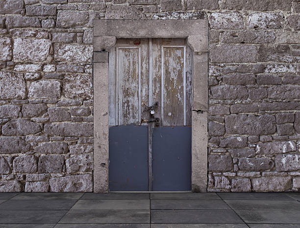 istock Old Wooden Door with a Padlock Against a Stone Wall 469274704