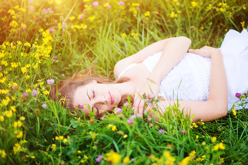 Attractive young woman with flowers outside on a meadow full of flowers.