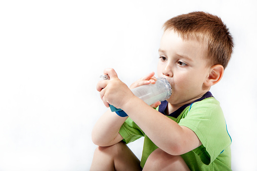 Little boy using inhaler for asthma isolated on white background