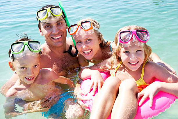 Scuba divers Portrait of cheerful family in aqualungs looking at camera with smiles scuba diving family stock pictures, royalty-free photos & images
