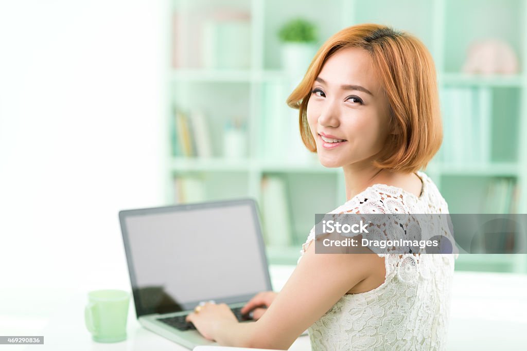 Freelancer Happy Korean woman working on laptop and looking at the camera 20-29 Years Stock Photo