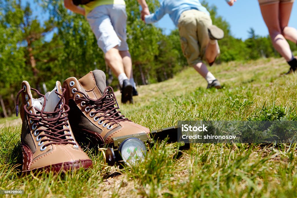 Trip equipment Image of pair of boots and compass on background of people running down green grass Camping Stock Photo