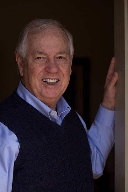 istock Smiling senior man with hand on an open door 469297658