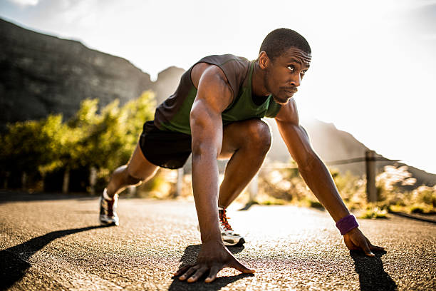 vestibilità atleta afroamericano in una posizione di partenza - running jogging african descent nature foto e immagini stock
