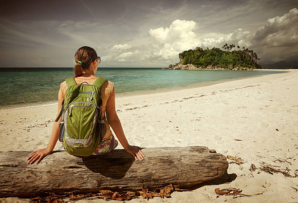 istock Young woman with backpack relaxing on coast and looking island 469299104