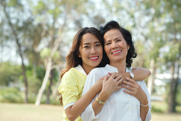 istock Daughter standing behind her mother with her arms around her 469310990
