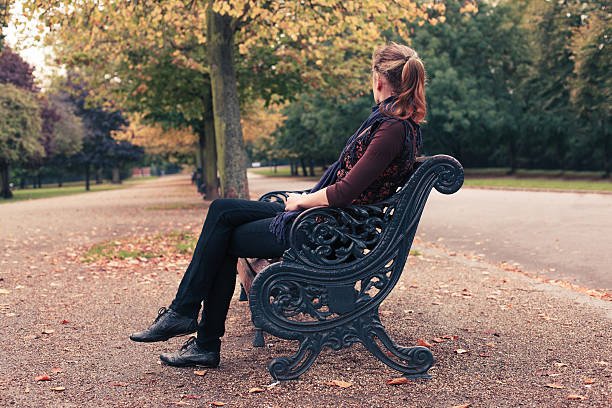 istock Young woman sitting on park bench 469311546