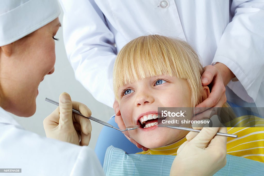 Dental checkup Image of little girl having her teeth checked by doctor and assistant 2015 Stock Photo