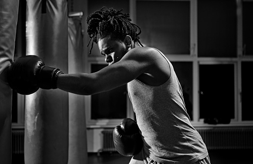 black boxer practicing with punch bag