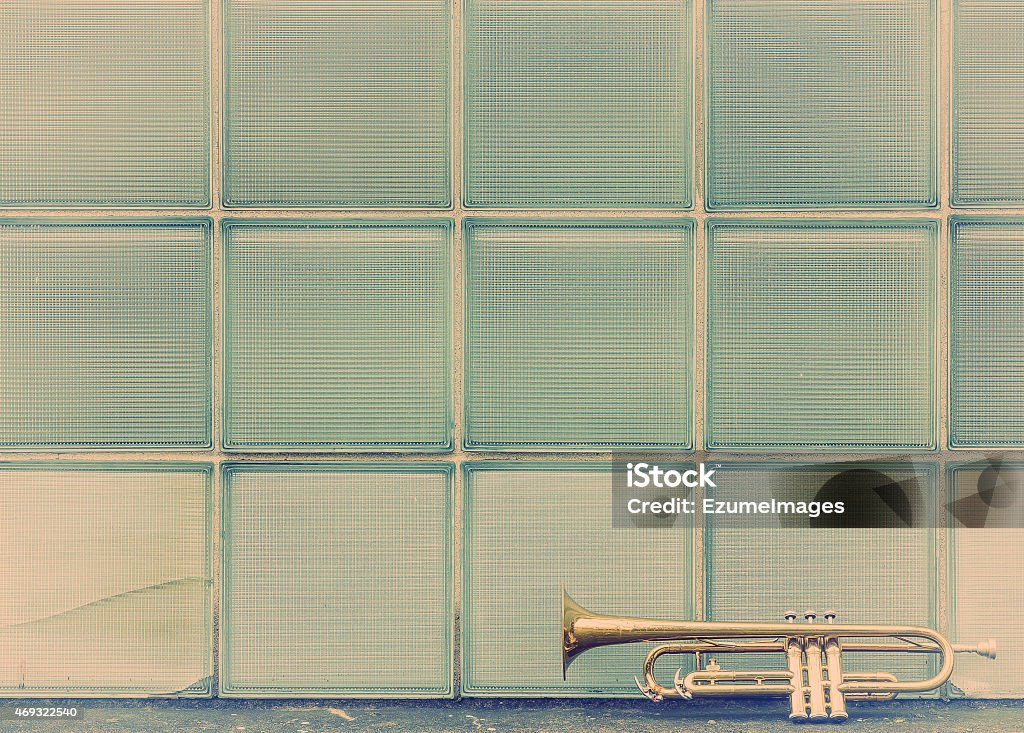 Old Trumpet Windows Old worn trumpet stands alone against a window background outside a jazz club 2015 Stock Photo