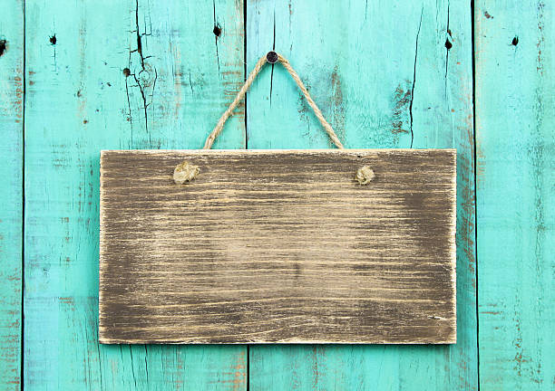 Blank rustic sign hanging on distressed wooden turquoise fence Blank wooden sign hanging on washed out teal blue distressed wood background barn doors stock pictures, royalty-free photos & images