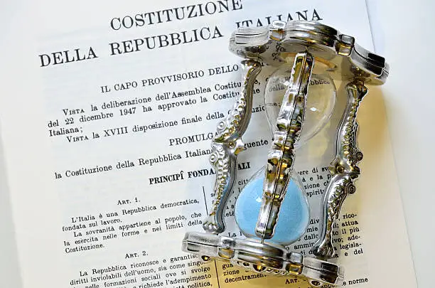 text of the Italian constitution with a silver hourglass with blue sand on it