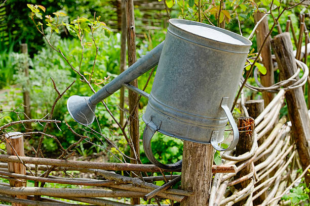 an old tin watering can hanging upside down on a wooden fence