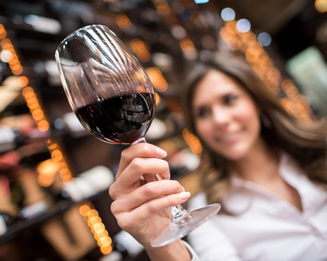Woman at a wine taste - focus on foreground on the glass