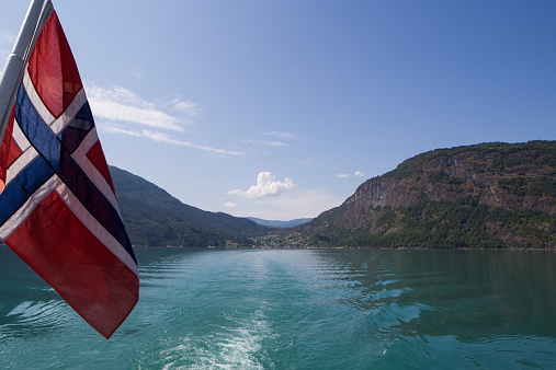 Norwegian flag housed on a ferry overlooking gorgeous fjords and mountains.