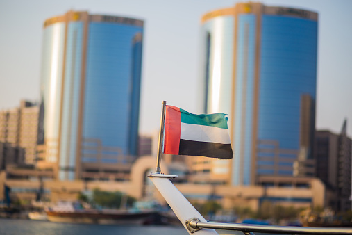 UAE Flag on a boat with bokeh background of twin towers at Dubai Creek.