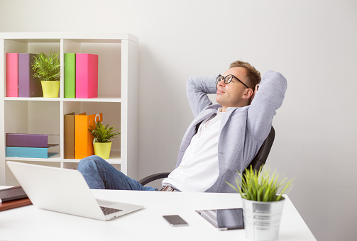 Relaxed businessman sitting in chair with hands behind head