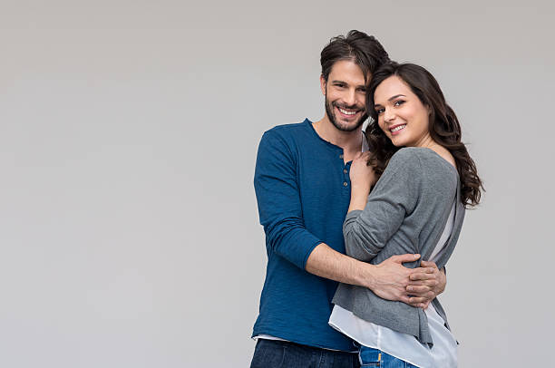 Happy couple embracing Portrait of happy couple looking at camera against gray background boyfriend stock pictures, royalty-free photos & images