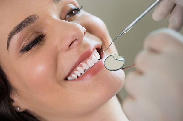 A young woman baring her teeth for the dentist to inspect Closeup of dentist examining young woman's teeth human teeth stock pictures, royalty-free photos & images