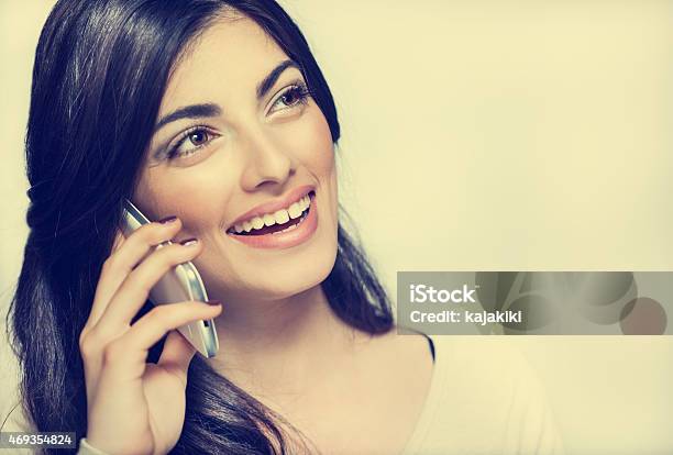 Hermosa Mujer Joven Sonriente Hablando Por Teléfono Foto de stock y más banco de imágenes de Adulto