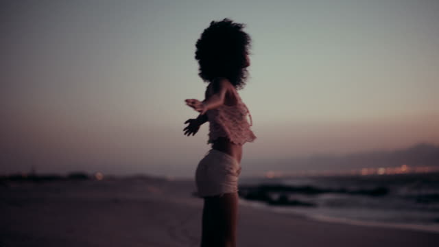 Teenage afro girl enjoying sunset at beach