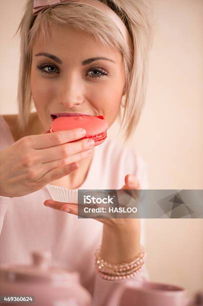 Young Beautiful Blond Woman Eating Macaroon While Having Teaparty Stock Photo - Download Image Now