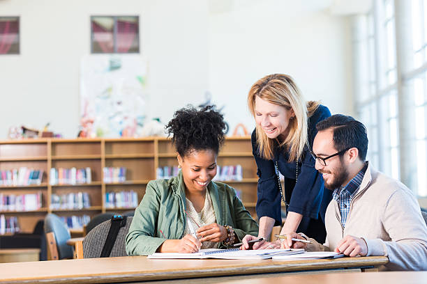 variegato gruppo di adulti che lavorano in biblioteca universitaria di grandi dimensioni - insegnante foto e immagini stock