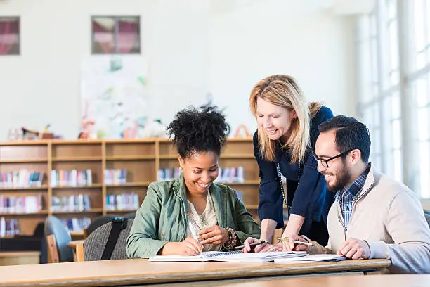 Photo of Diverse study group of adults working in large college library