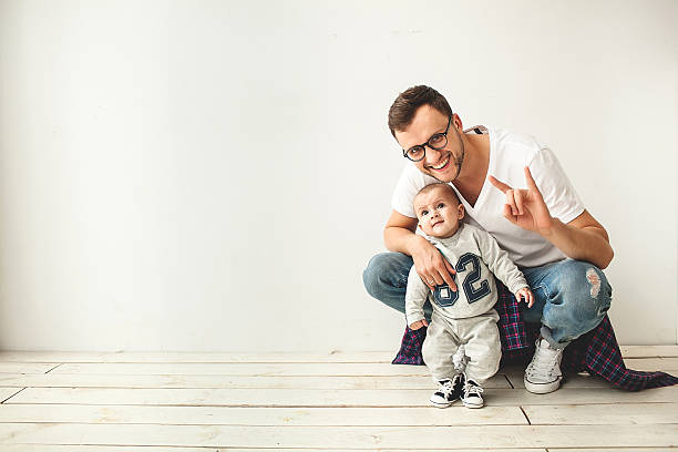 Young hipster father and baby boy on wooden floor stock photo